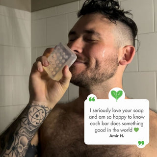 User generated content of a happy smiling male customer inhaling the fresh scent of the aloe vera bar soap in the shower with a quote that says I seriously love your soap and am so happy to know each bar does something good in the world